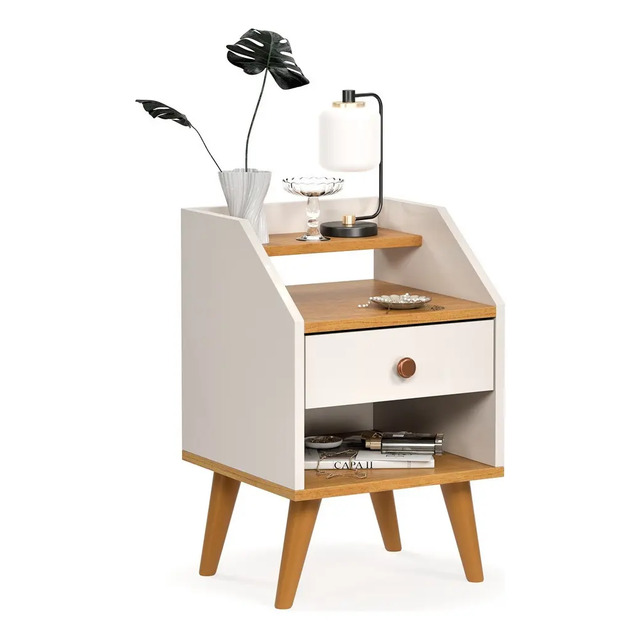 Mesa de cabeceira clássica de cor branca e madeira com uma gaveta, nicho superior, nicho inferior e pés retrô, decorada com um vaso, luminária e livros.
