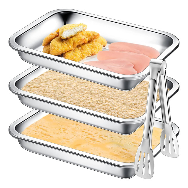 Conjunto de 3 assadeiras de aço inoxidável empilhadas sendo utilizadas para o processo de empanar frango, acompanhadas por um pegador de metal posicionado ao lado.