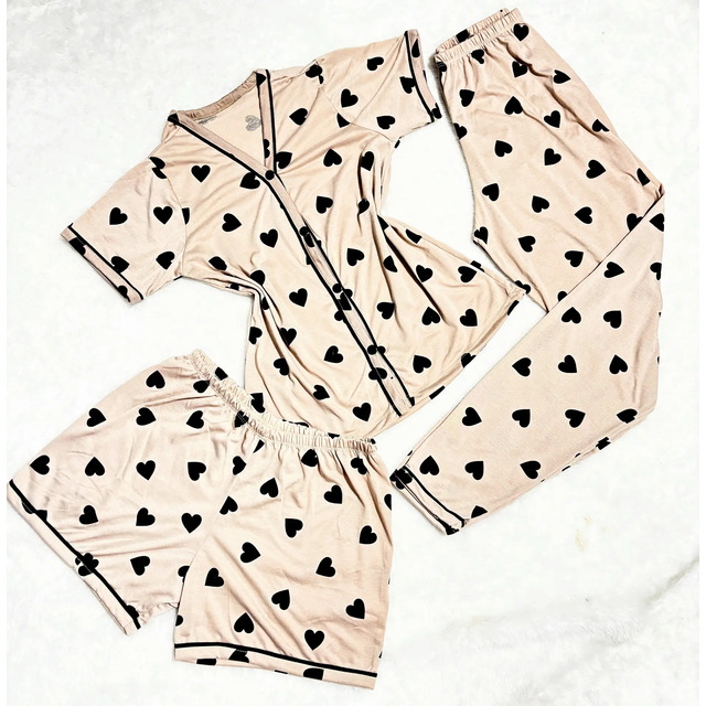 Kit de pijama americano de três peças em tom bege com estampa de corações pretos, contendo uma camisa de botões, uma calça comprida e um short.