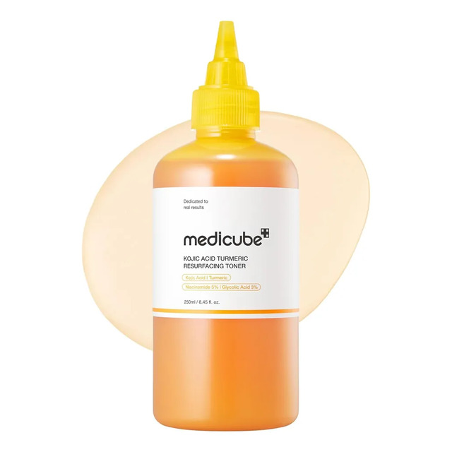 Frasco de Tônico Facial Medicube com tampa amarela, contendo 250ml de produto, com rótulo destacando Ácido Kójico, Cúrcuma, Niacinamida 5% e Ácido Glicólico 3% sobre um fundo de mancha amarela.