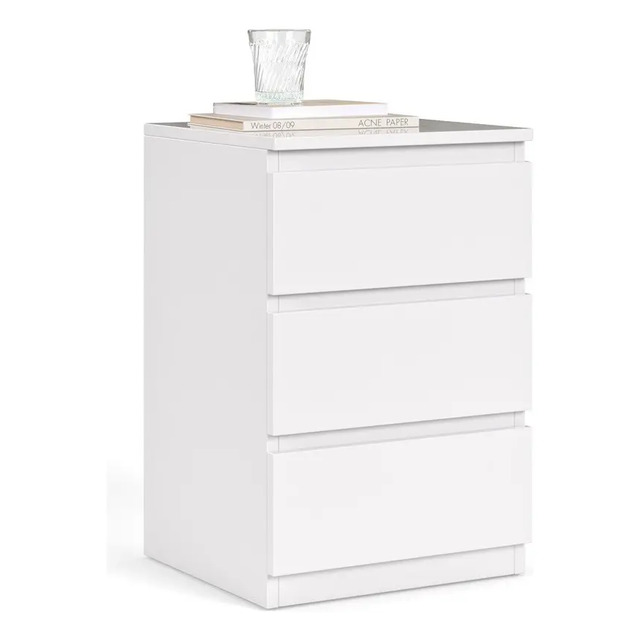 Mesa de cabeceira branca de estilo retrô com três gavetas fechadas, exibindo um copo e livros sobre o tampo superior em fundo branco.
