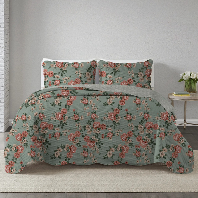 Kit colcha cobre leito king com estampa floral estilo patchwork sobre cama, acompanhado de dois porta-travesseiros coordenados em ambiente de quarto com mesa lateral