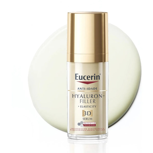 Frasco do sérum facial Eucerin Hyaluron-Filler + Elasticity 3D de 30ml com tampa dourada sobre um fundo branco com uma mancha de creme ao fundo