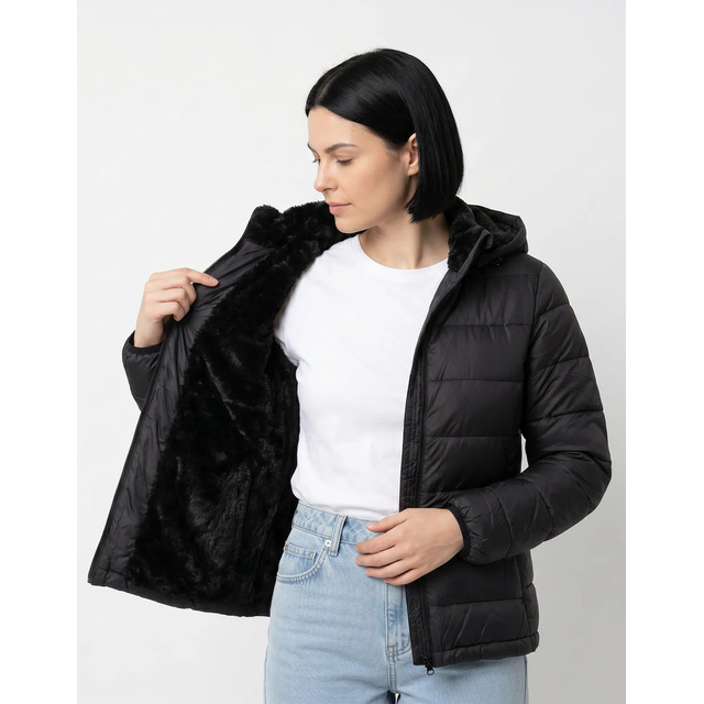 Mulher vestindo jaqueta preta modelo puffer com forro de pelinhos interno, exibindo o capuz e o fechamento em zíper.