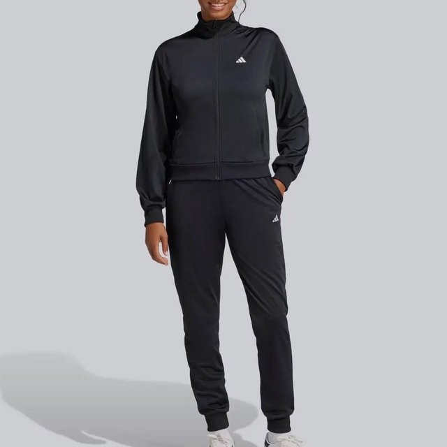 Modelo vestindo conjunto de agasalho esportivo Adidas feminino na cor preta, composto por jaqueta com zíper e calça combinando.