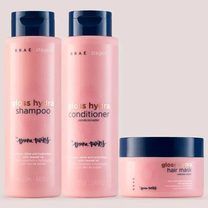 Kit de tratamento capilar Braé Stages by Bruna Tavares contendo um frasco de shampoo, um frasco de condicionador e um pote de máscara capilar, todos na cor rosa com tampa azul escuro.