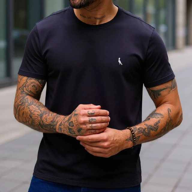Homem vestindo camiseta preta lisa da marca Reserva com o logo do pica-pau bordado no peito
