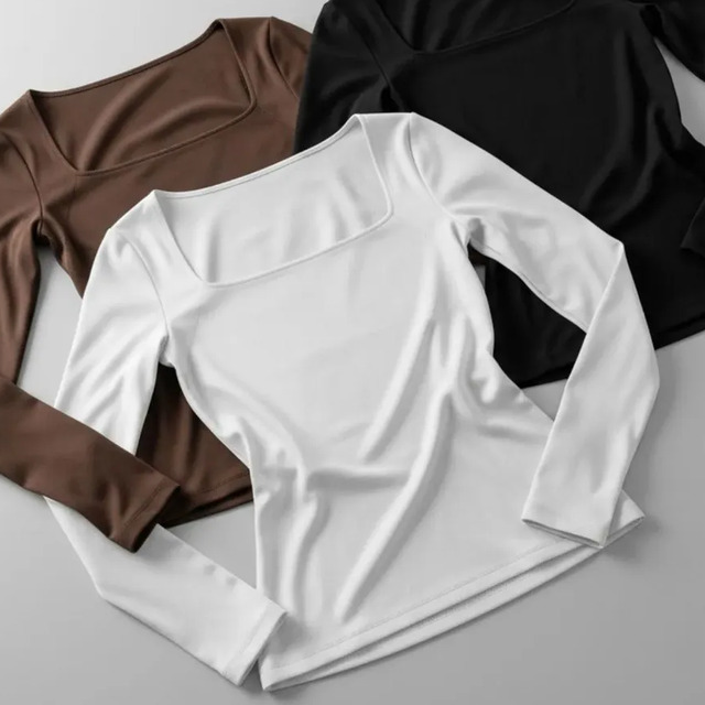 Kit com três blusas de manga longa com decote quadrado nas cores marrom, branco e preto dispostas sobre uma superfície cinza