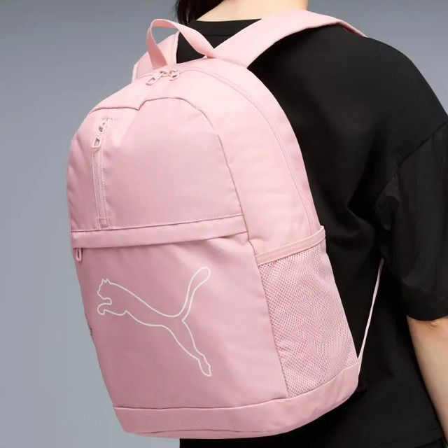 Mochila Puma Plus Backpack na cor rosa sendo usada nas costas, exibindo o logo da marca em branco na parte frontal e bolso lateral em tela