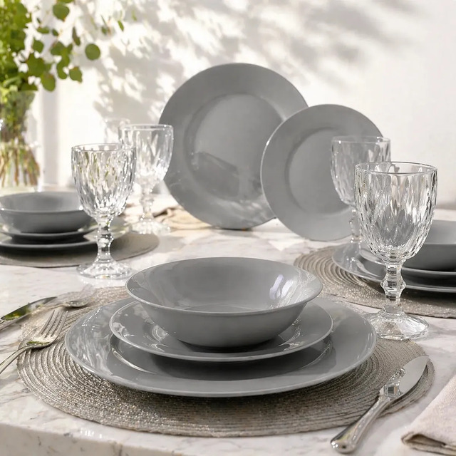 Conjunto de aparelho de jantar com 16 peças de vidro na cor cinza, incluindo pratos rasos, pratos fundos e taças de vidro modelo Diamond dispostos sobre uma mesa posta.