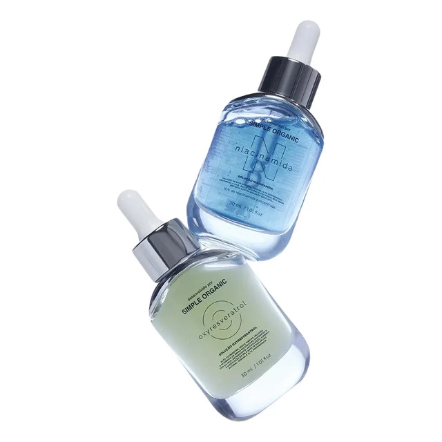 Dois frascos de sérum da Simple Organic, um com líquido azul contendo Niacinamida e outro com líquido esverdeado contendo Oxyresveratrol, ambos com conta-gotas.