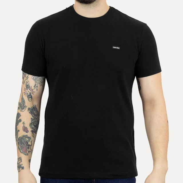 Camiseta masculina Calvin Klein na cor preta, confeccionada em tecido piquet, exibindo um pequeno logo da marca no lado esquerdo do peito.