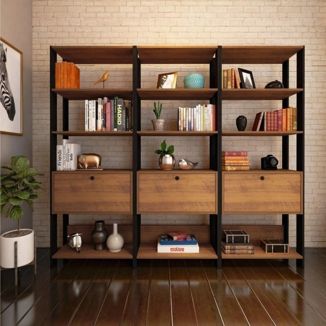 Conjunto de três estantes estilo industrial em tom marrom com prateleiras abertas e uma porta inferior cada, decoradas com livros e objetos em um ambiente com parede de tijolinhos.