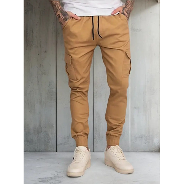 Homem vestindo calça cargo jogger cor bege claro com seis bolsos e tênis casual