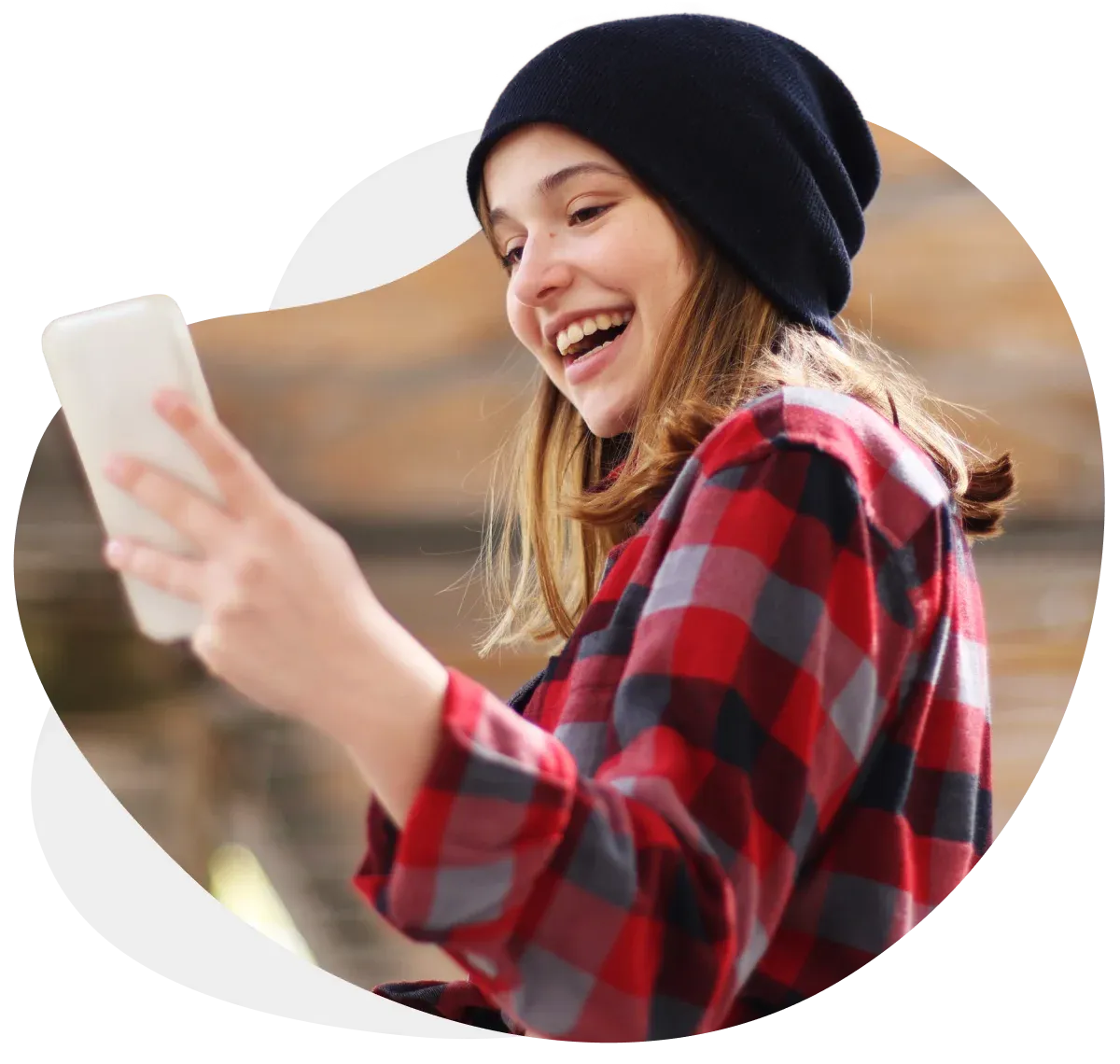 Una adolescente sonriendo con un teléfono celular en la mano.