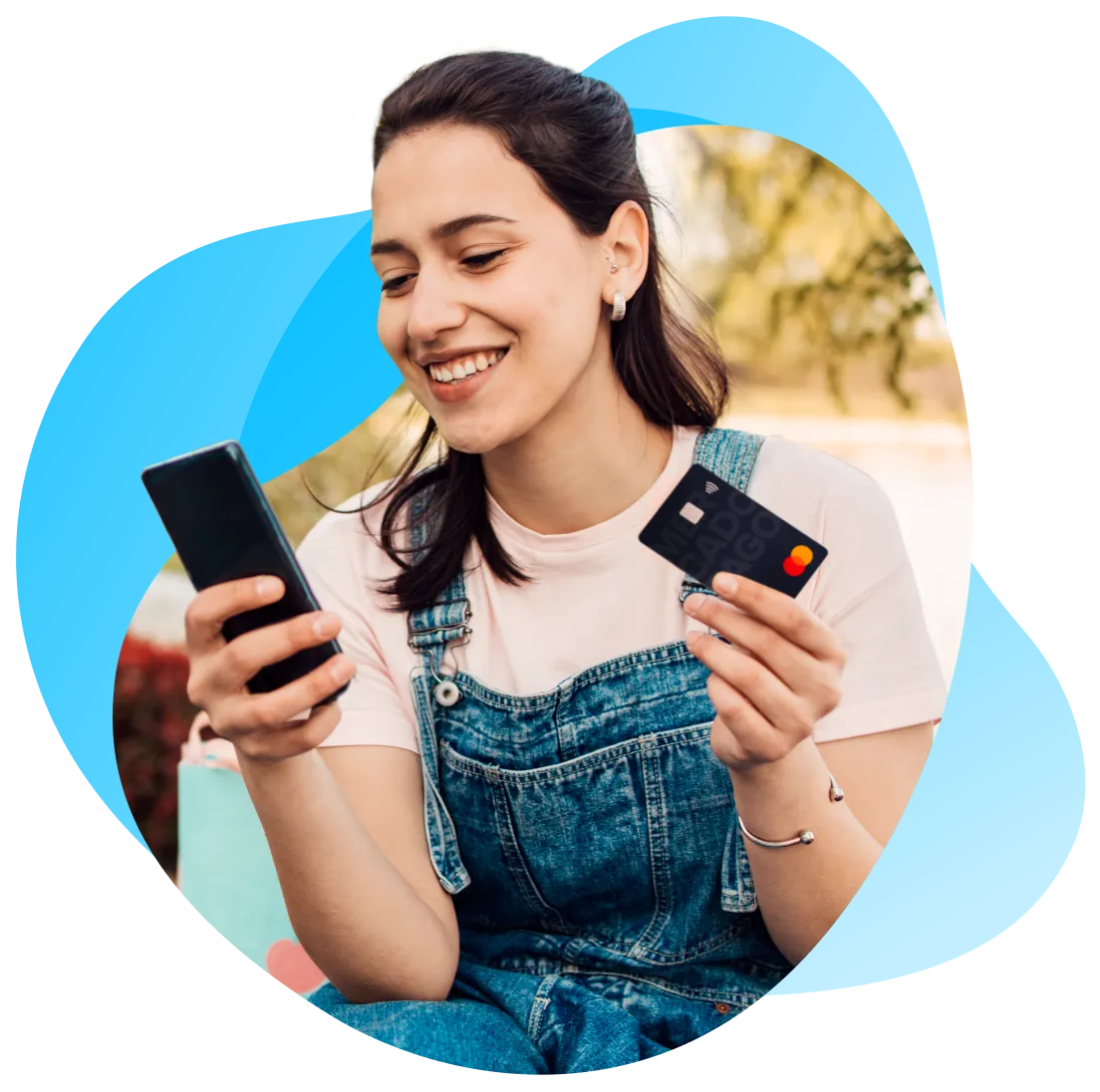 Chica argentina que sostiene un teléfono celular en la mano derecha y una tarjeta de crédito o tarjeta de débito en la mano izquierda.
