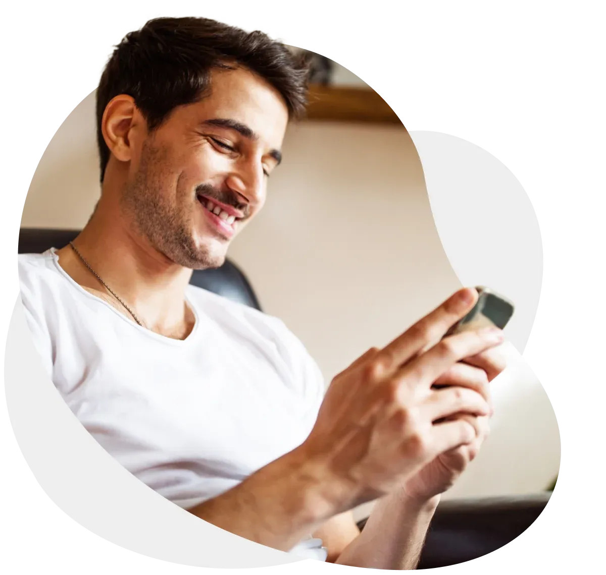 Un hombre sonriendo con un teléfono celular en la mano.