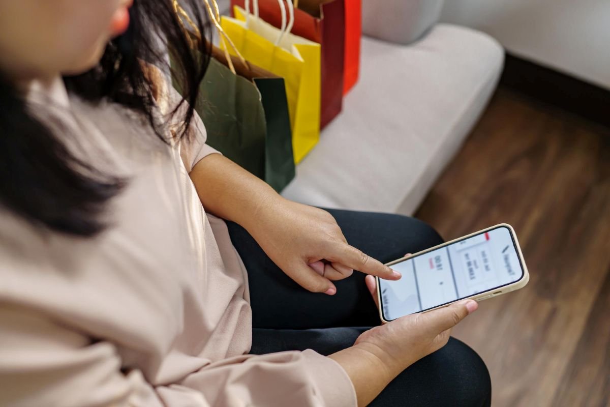 Cliente segurando smartphone com tela do WhatsApp Business aberta mostrando catálogo de produtos.