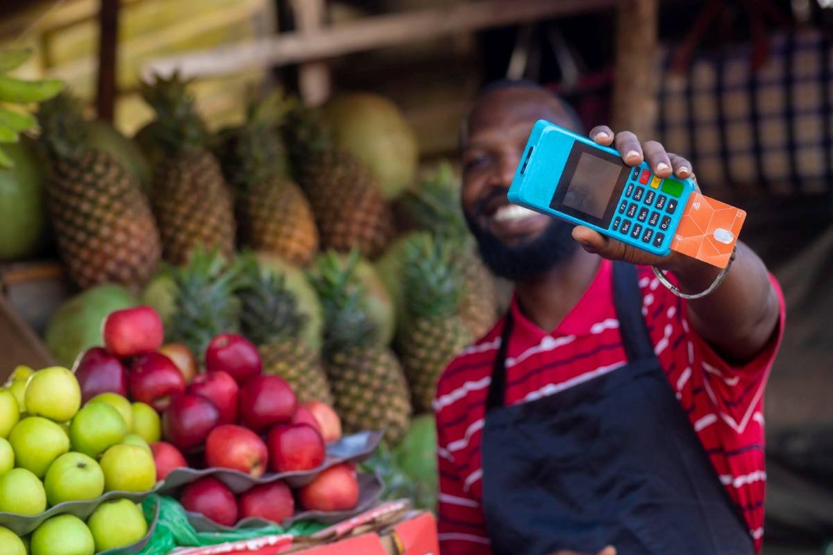 Empreendedor usando maquininha de cartão portátil em uma barraca de feira ao ar livre