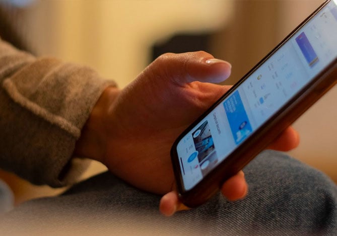 Mão de uma pessoa segurando o smarpthone aberto no app do Mercado Pago para usar a ferramenta de gestão de custos em seu negócio