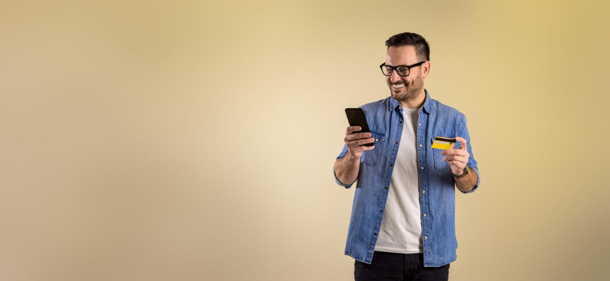 Homem sorrindo com celular e cartao nas maos