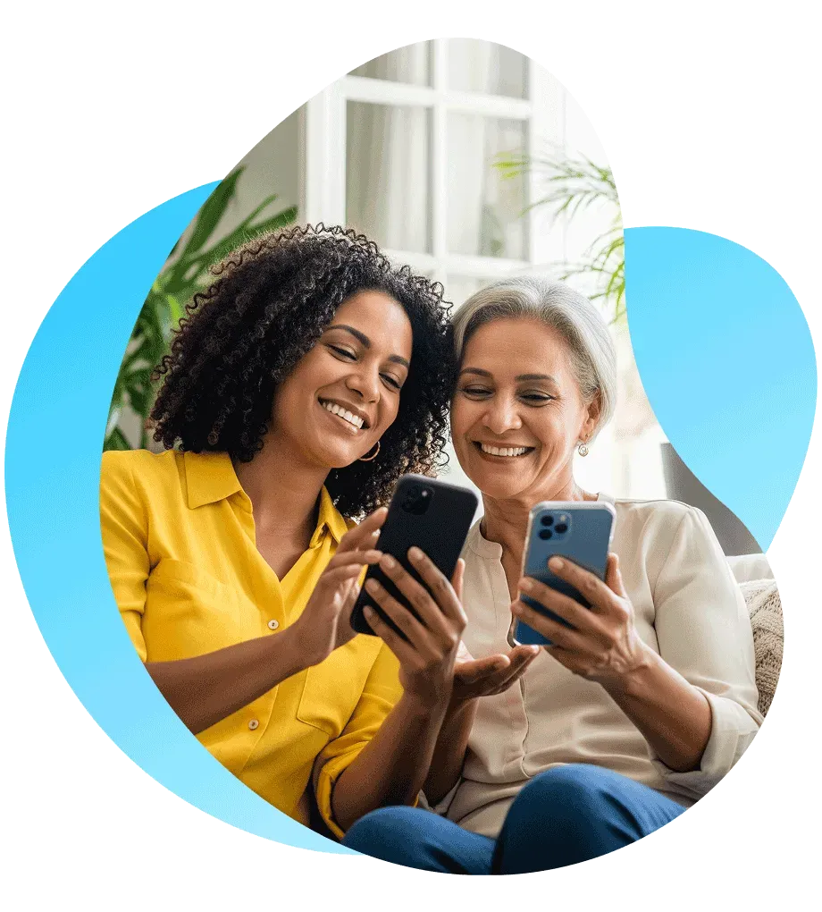 Uma mulher mostra o celular a outra mulher para recomendar o uso do Mercado Pago.