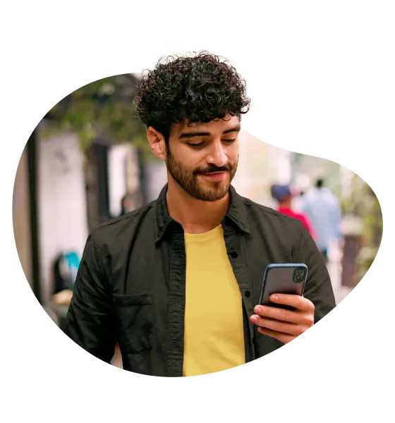 Una persona usa su cuenta de Mercado Pago en su celular mientras sonríe.