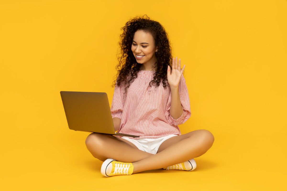 Mulher sorridente com laptop acenando para videoaula