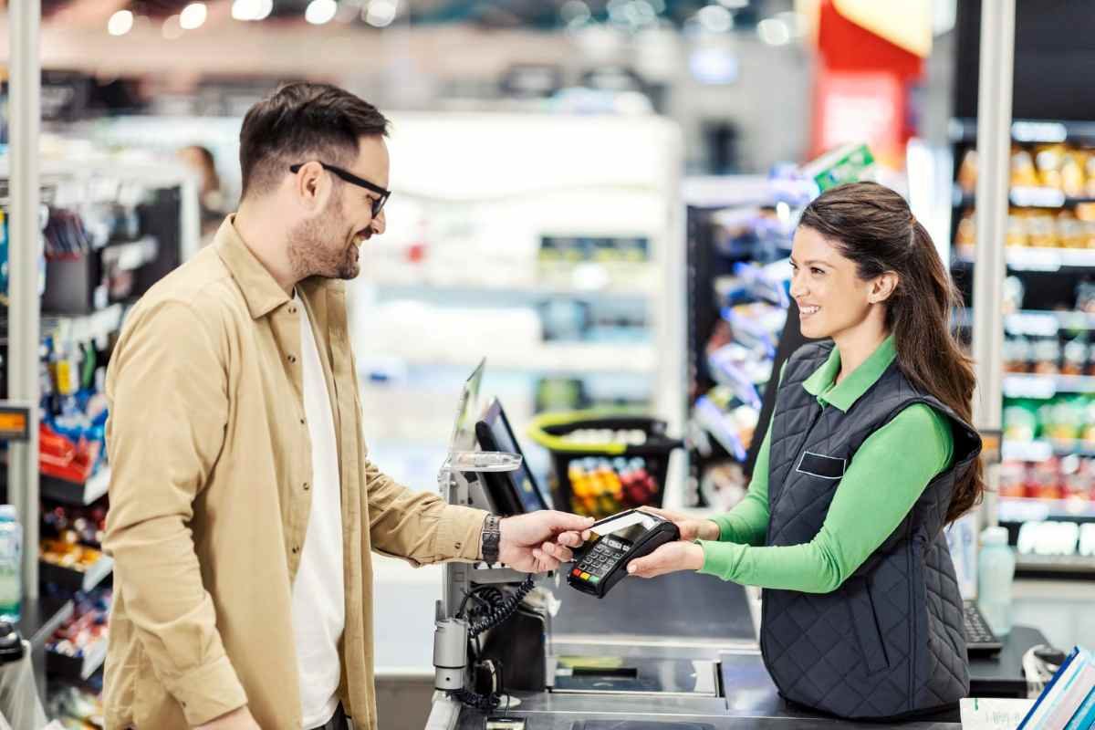 Operadora de caixa em supermercado usando maquininha de cartão.