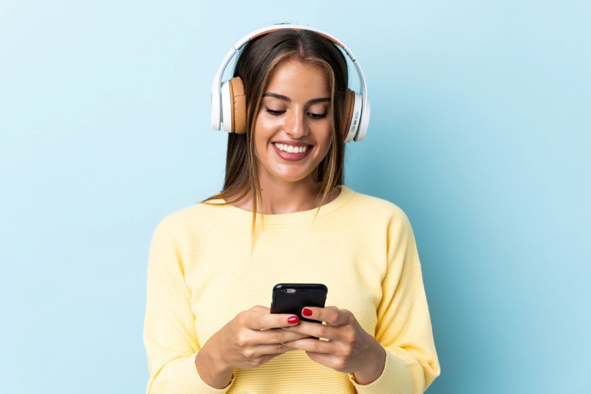 Mulher usando celular e fone de ouvido usando sua assinatura Spotify