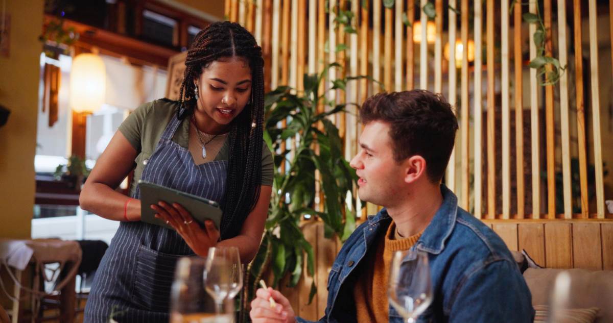 Atendente de restaurante recebendo pedido do cliente com sistema digital de comandas