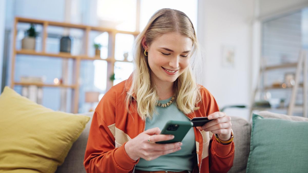 Mulher usando cartão de crédito recarregável no  celular