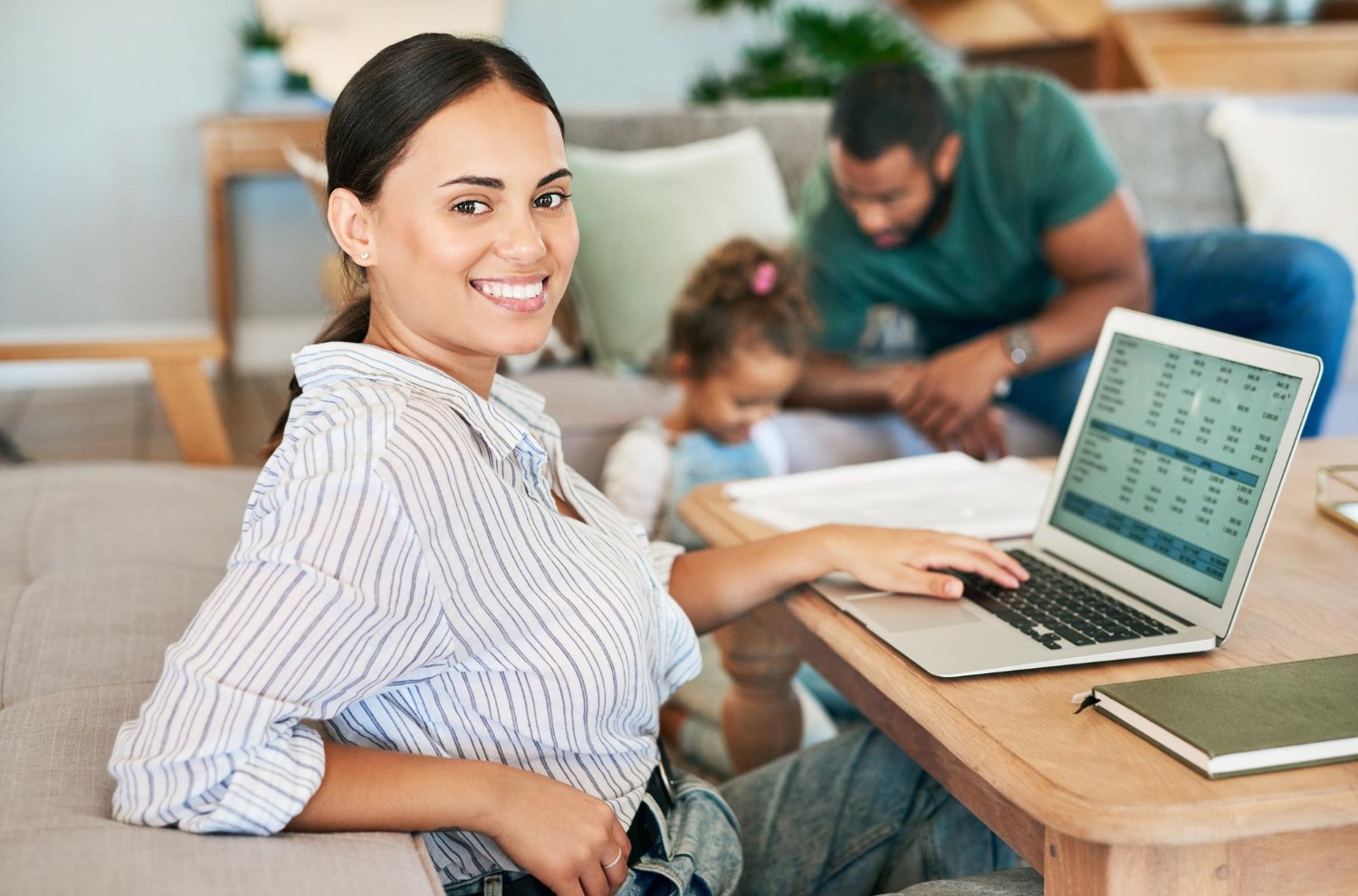 Casal com criança pequena revisando contas no computador em casa.