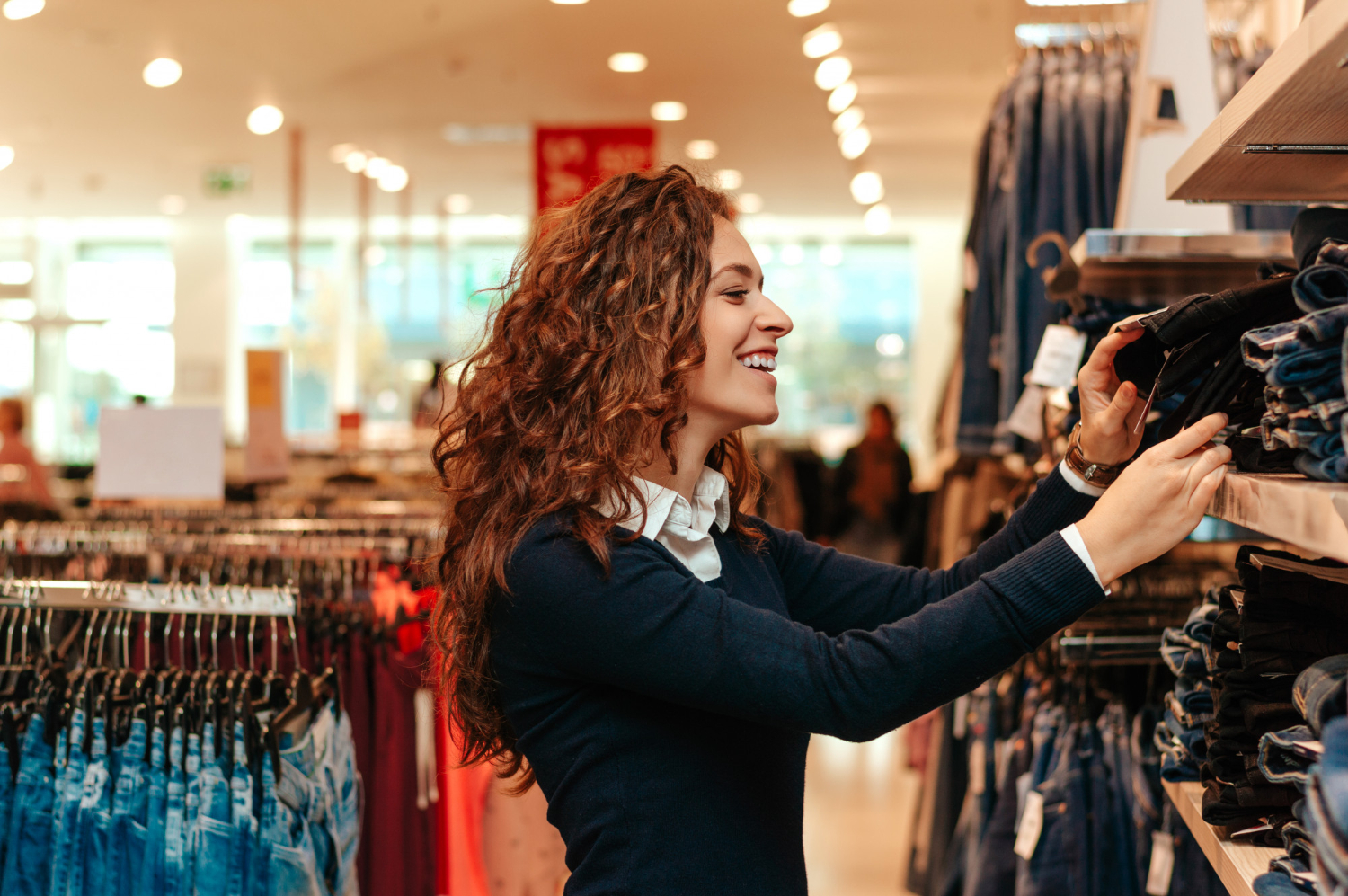 Cliente feliz em loja de roupas física sentindo a textura das peças