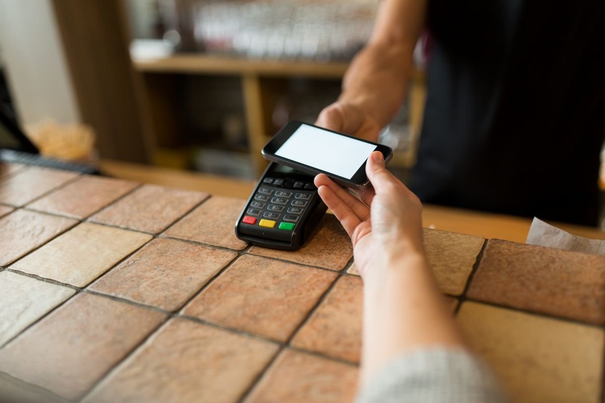 Vendedor cobrando cliente com Point Pro 3 em um balcão de loja.