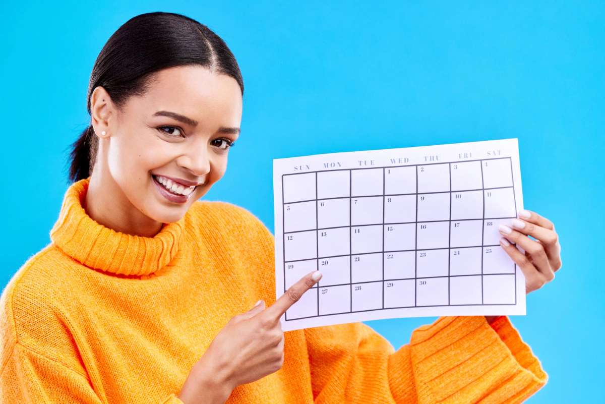 Mulher aponta para calendário de pagamentos recorrentes.