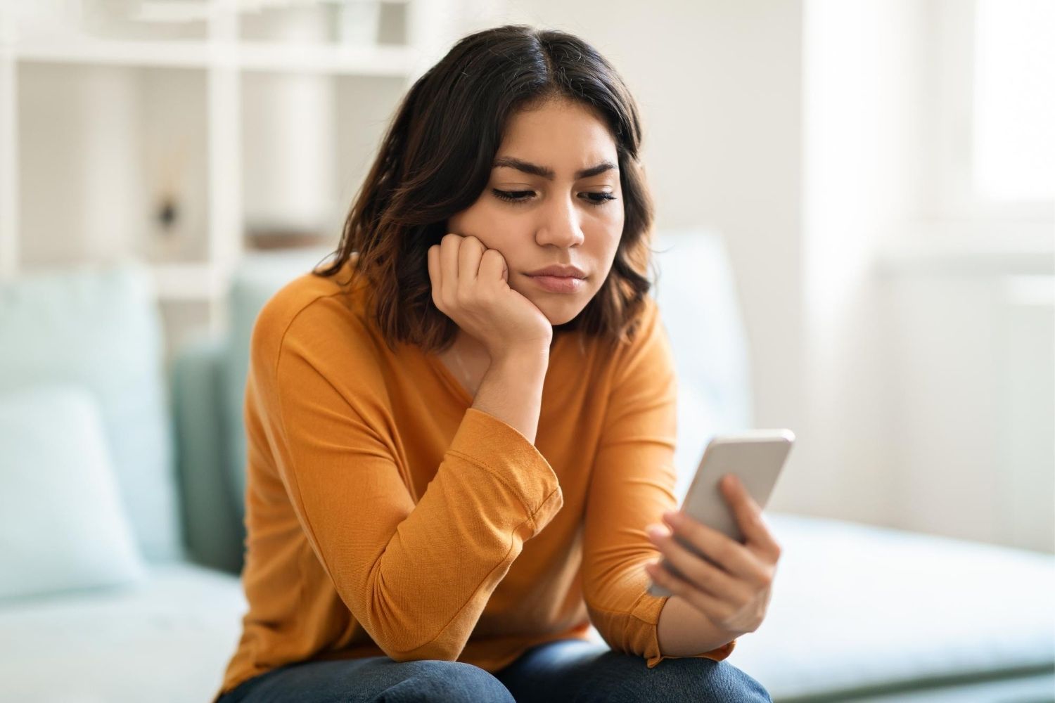 Mulher usa celular preocupada pensando se caiu em golpe digital