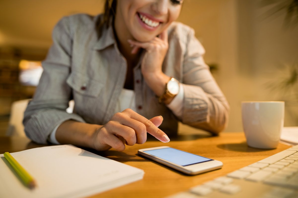 Mujer sonriente frente a su teléfono celular