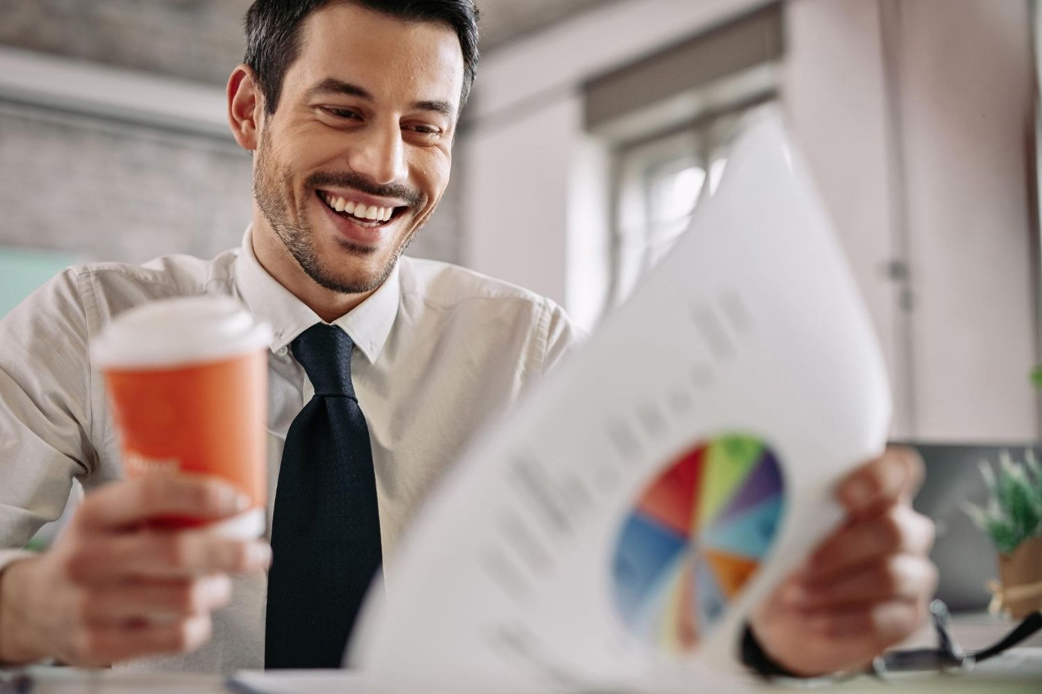 Homem sorri segurando café e observando gráficos do seu capital social integralizado