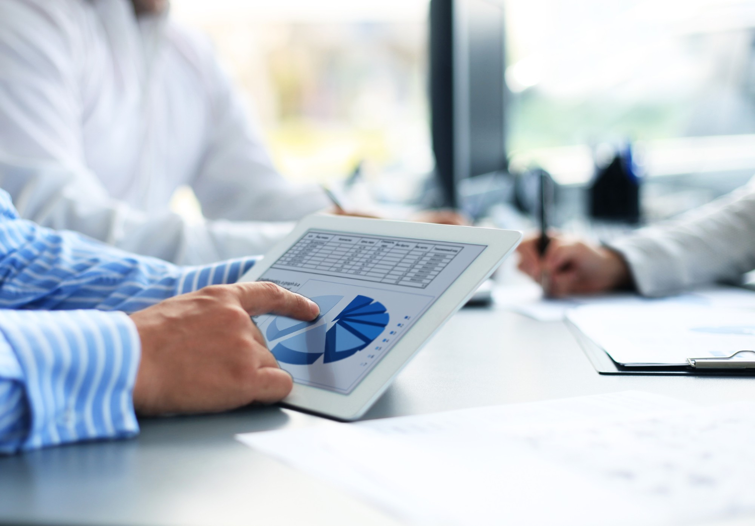 Homem manuseia tablet com gráficos de fluxo financeiro.