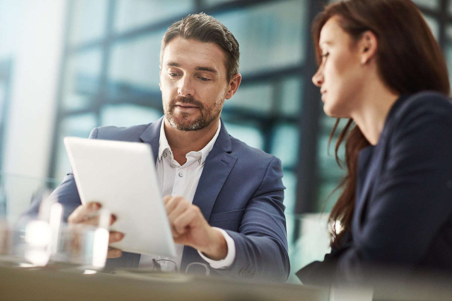 Homem mostra tablet para mulher em ambiente empresarial