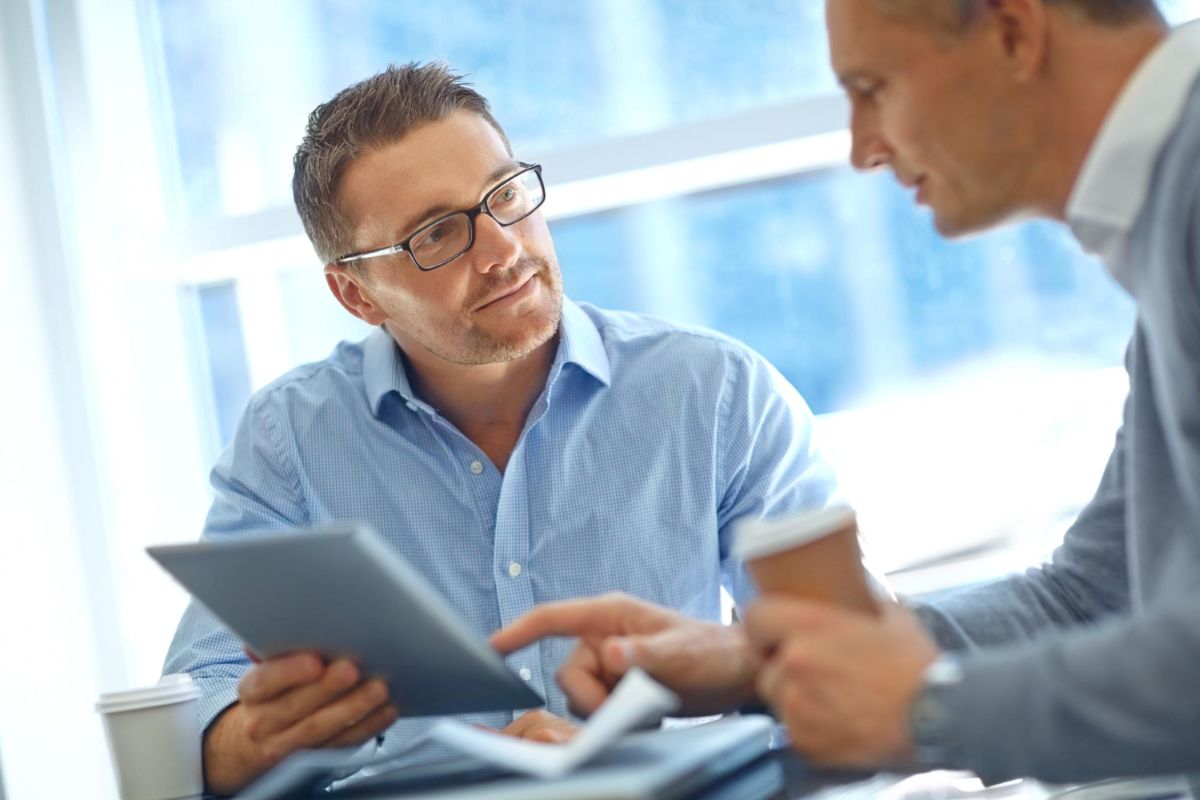 Homens conversam enquanto um segura um tablet