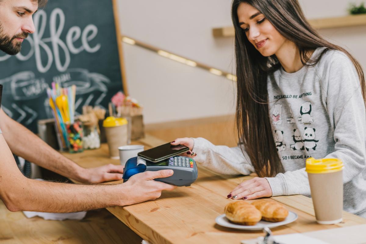 joven-pagando-en-negocio-con-celular