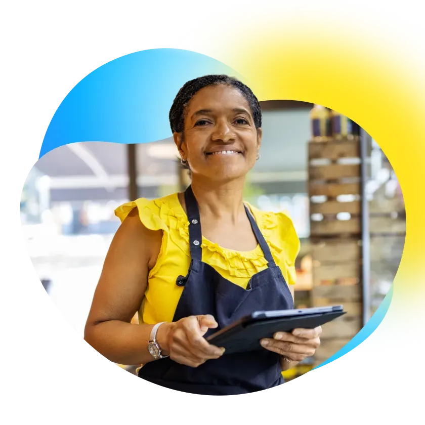 La dueña de una tienda de ropas, en pie, sonriendo.
