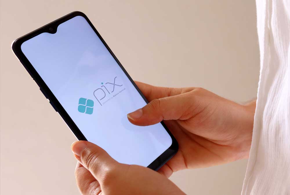Uma mão pagando DAS MEI com Pix no Mercado Pago - Pagar DAS MEI com Pix