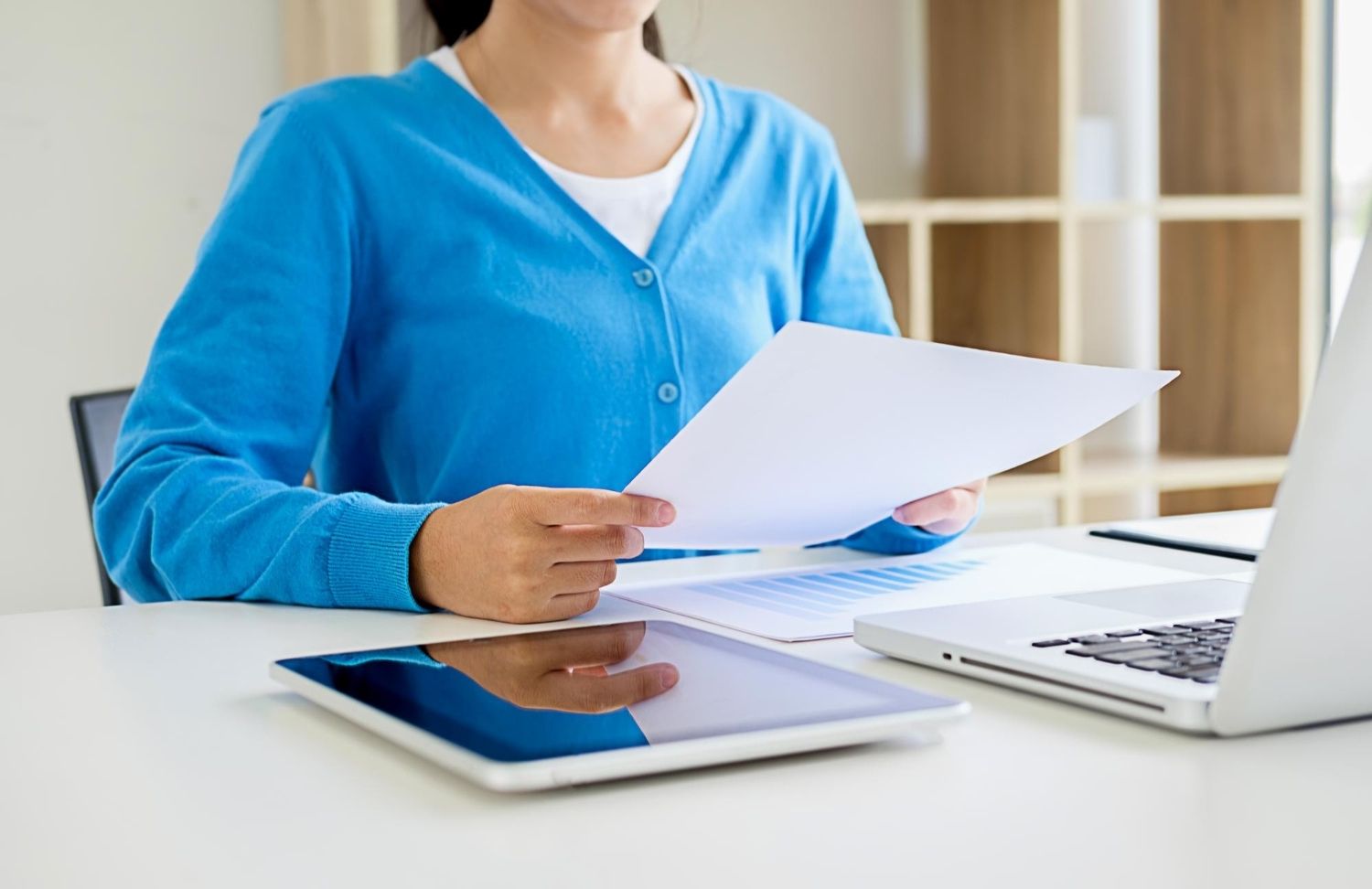 Mulher com notebook e tablet analisando extrato bancário