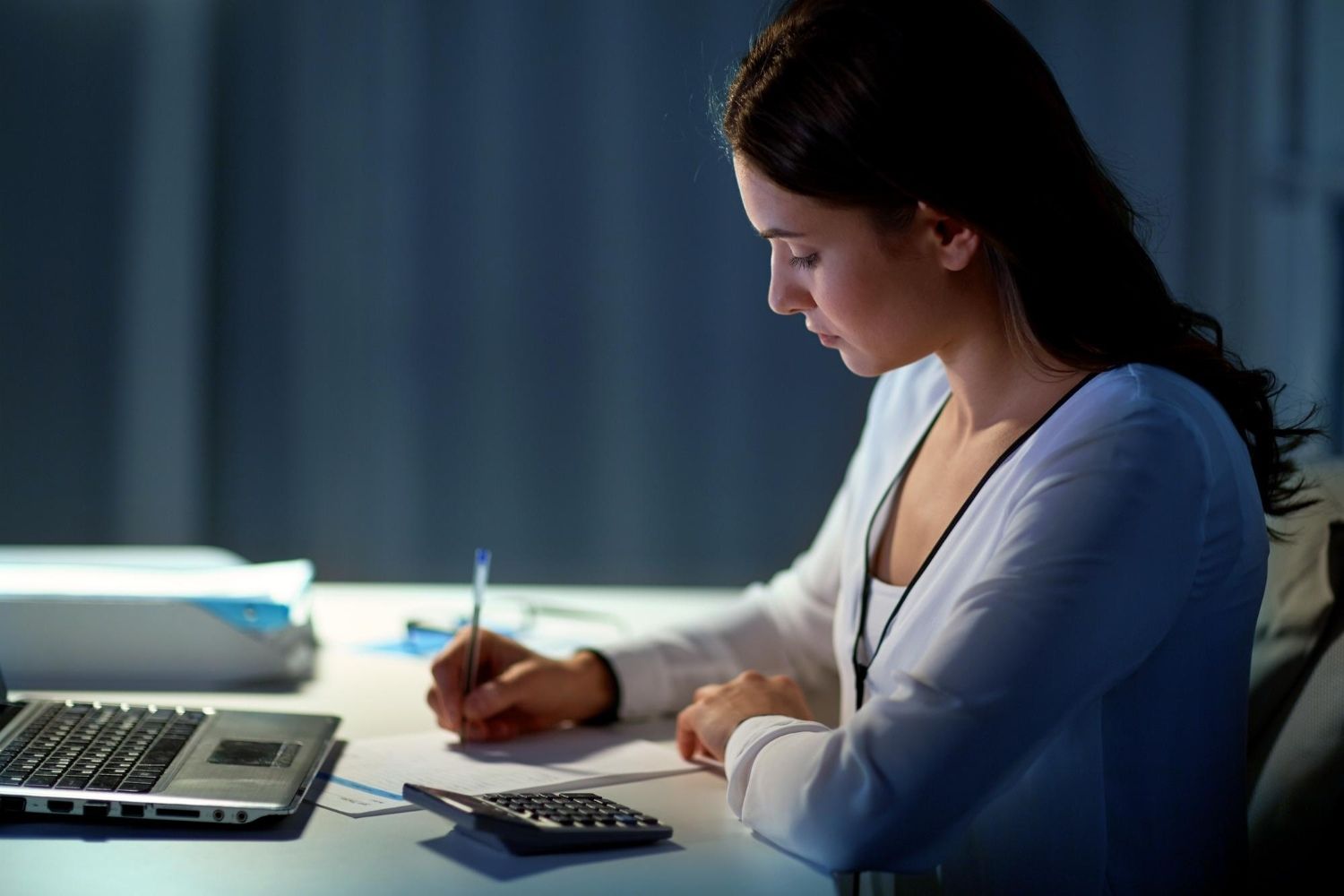 Mulher com caderno e notebook analisando melhores opções para guardar dinheiro