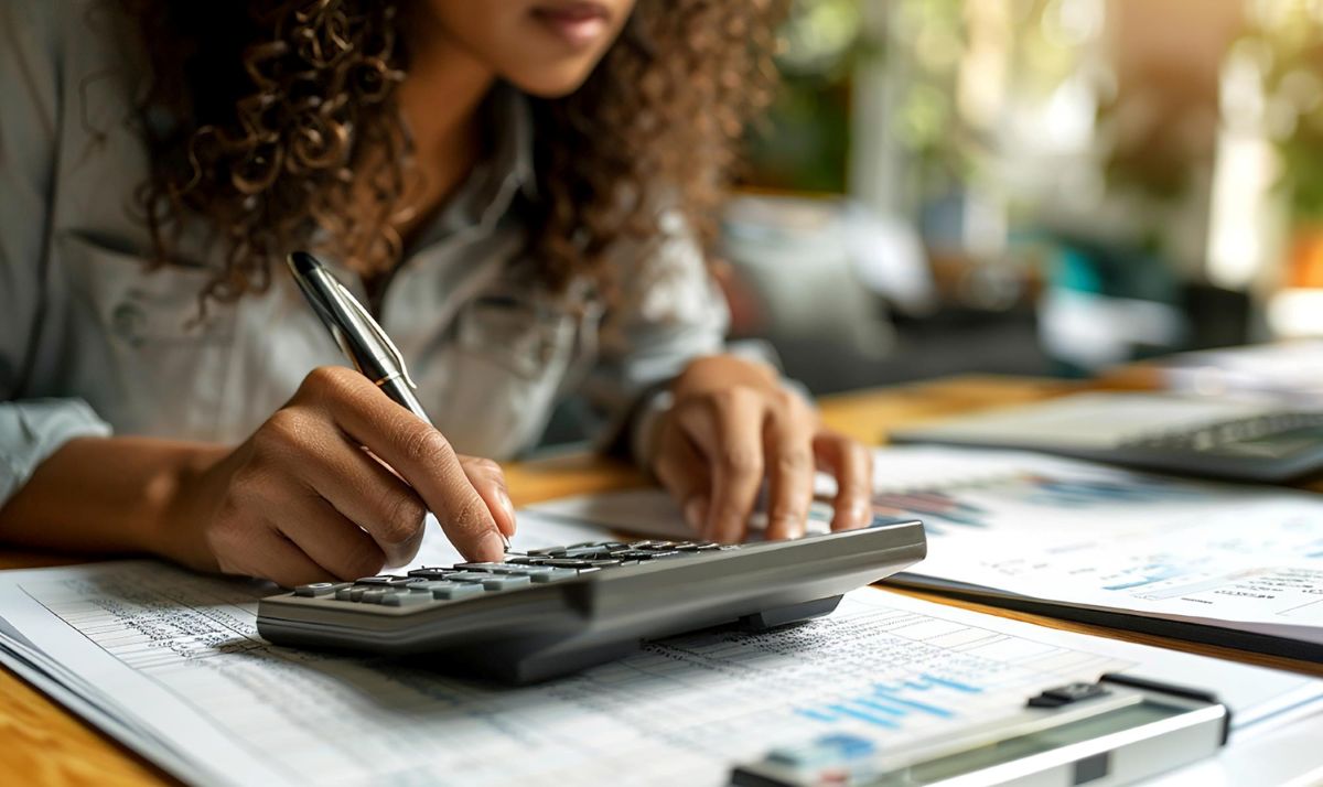Mulher com calculadora comparando rentabilidade de investimentos