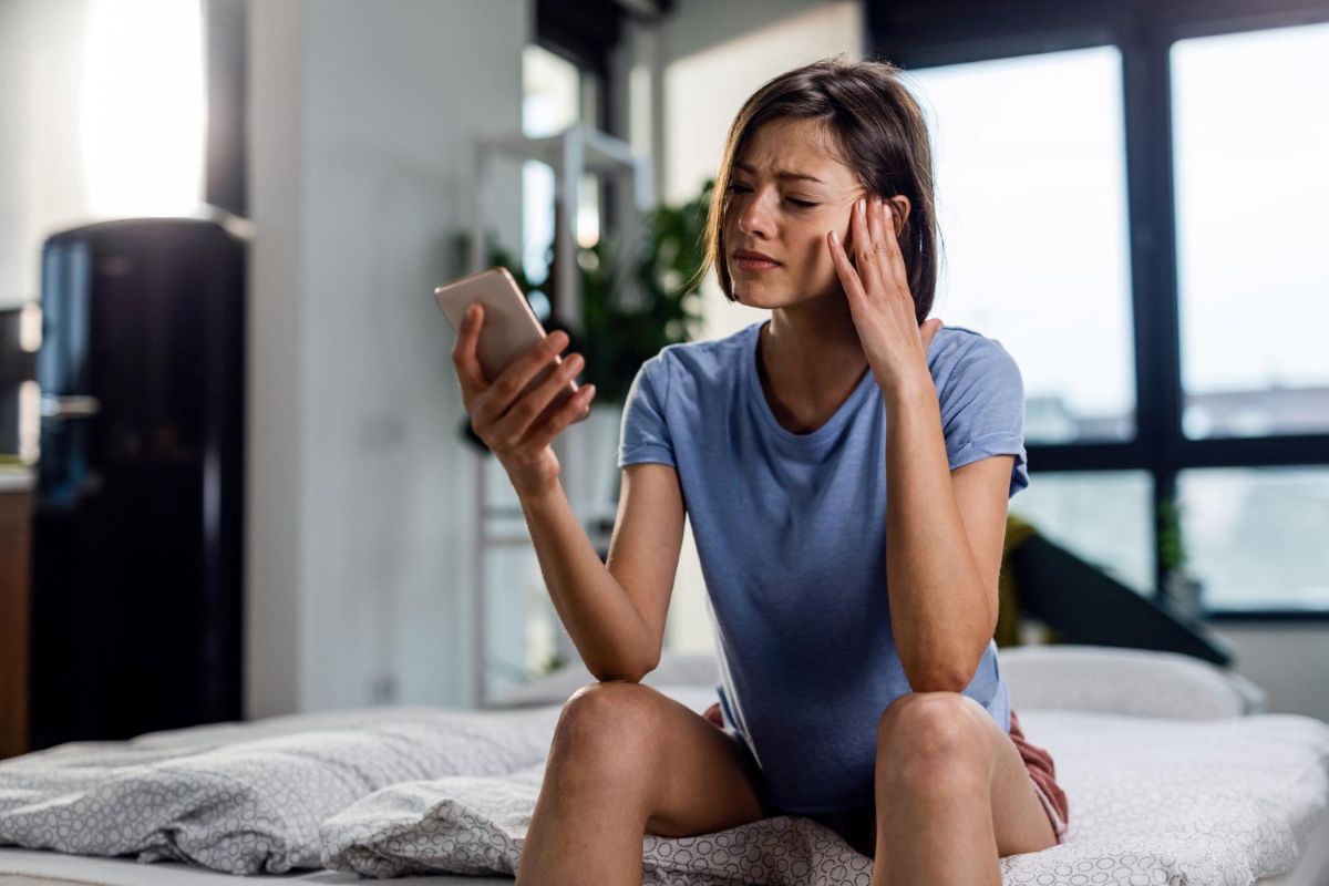 Mulher usa celular preocupada verificando se seu celular está com um malware