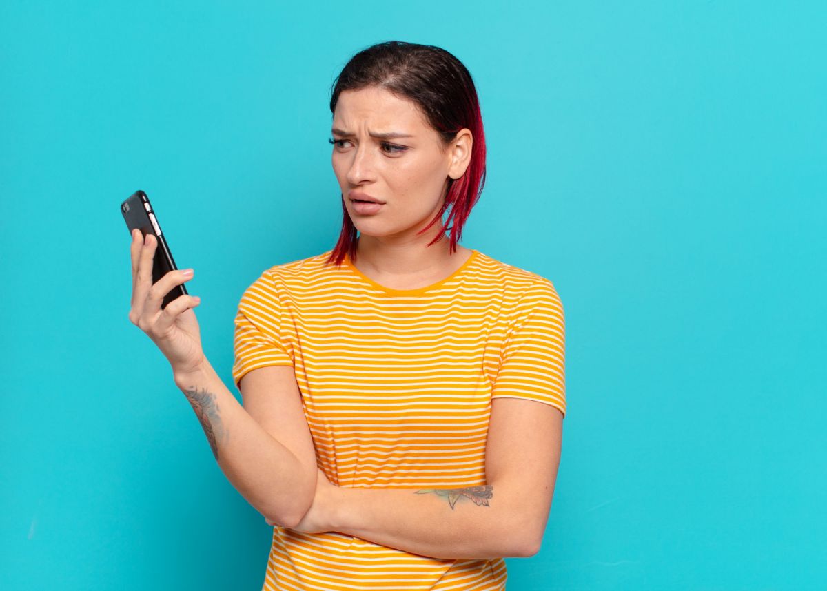 Mulher com olhar preocupado usando celular para tentar cancelar um Pix